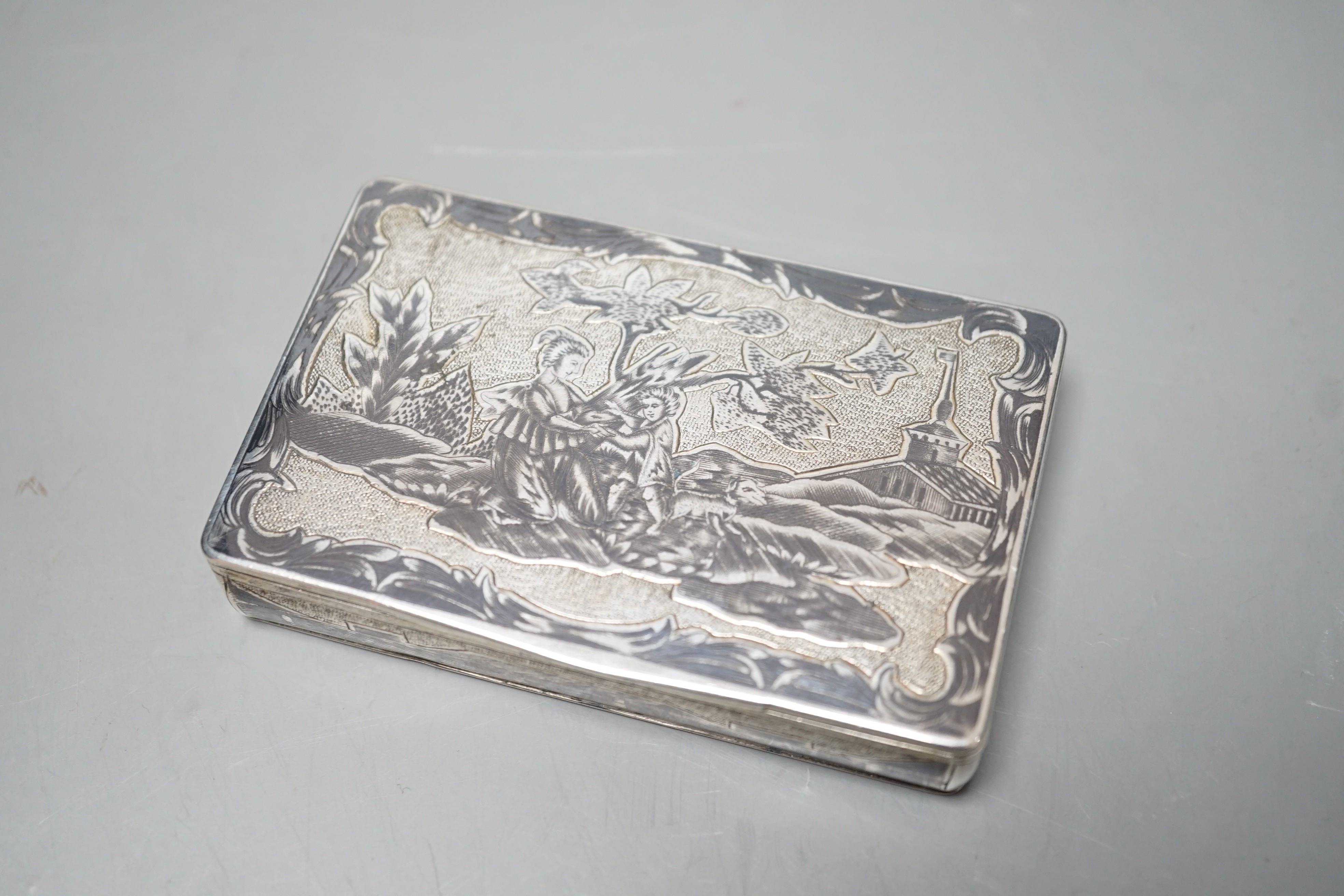 A late 19th century Russian 84 zolotnik and niello snuff box, decorate with figures in a landscape, 85mm.